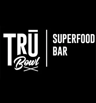 Logo for TRU Bowl Superfood Bar with bold white text on a black background, featuring "TRU Bowl" and "SUPERFOOD BAR" separated by a vertical line, capturing the vibrant energy of "a taste of rio.